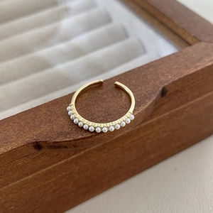Macro detail of gold plated adjustable ring set featuring delicate pearl embellishments
