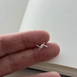 Minimalist 925 sterling silver barbed wire knot stud earrings shown on fingers