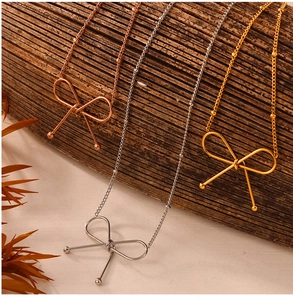 Detailed view of bow pendant necklaces in gold, silver, and rose gold on a wood surface