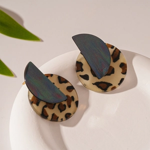 Detail view of retro leopard print acrylic round earrings with golden needles on a white tray