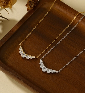Detailed macro view of gold and silver smile necklaces with zircon on dark wood