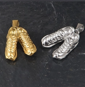 Macro detail of 3D miniature sneakers pendants in gold and silver finish on rock