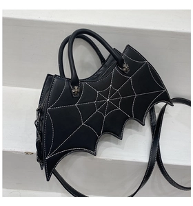 Close-up of black bat-shaped bag with white spider web stitching and cross metal hardware