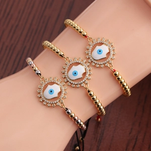 Trois bracelets mauvais œil de 4 mm en or, argent et or rose portés au poignet d'un modèle