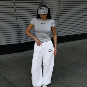 Photo en extérieur d'un t-shirt gris ajusté et d'un jogging blanc avec casquette de sport