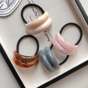 Detaillierte Nahaufnahme von Marmormuster-Acrylhaargummis in Creme, Rosa, Grau und Bernstein