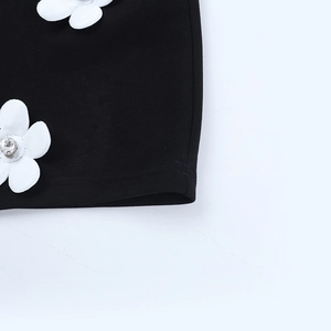 Détail de fleur 3D blanche avec cristal sur une robe noire à manches longues