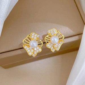 Elegant gold earrings with pearls and crystals on a silk jewelry display box