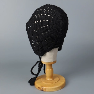 Vue détaillée du bonnet au crochet noir fait main avec motif ajouré et pompons bohèmes
