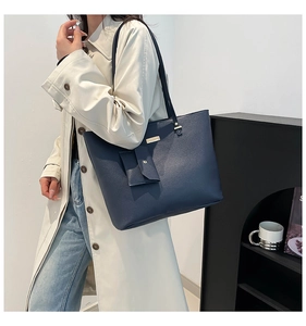 Detail of dark blue leather tote bag with lychee texture and gold metal hardware