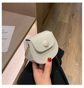 Détail d'un mini sac selle blanc avec bandoulière en chaîne dorée et cuir texturé fin
