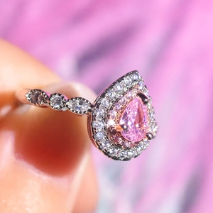 Macro shot of pear cut pink moissanite ring with halo stones in platinum plated setting