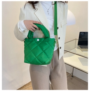 Detail of bright green quilted bucket bag with white magnetic snap and wide woven strap