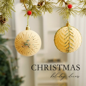 Creamy flocked Christmas tree ball ornaments with glitter details hanging on pine branches