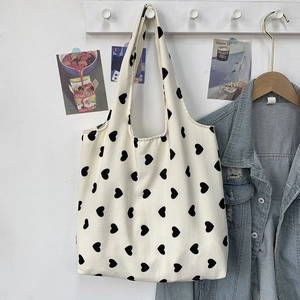 Detail of canvas tote bag with black heart patterns hanging in an INS style aesthetic room