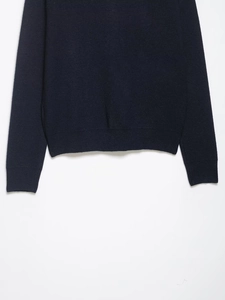 Close-up of ribbed cuffs and hem on a navy blue knit sweater with fine texture