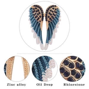Detailed view of angel wing brooch showing blue rhinestones and oil drop finish
