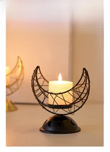 Detail of black crescent moon metal incense burner with hollow stars and white candle