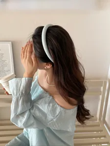Detail of light blue checkered sponge headband on model in cozy home setting