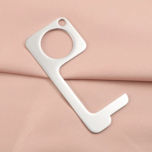Detailed macro shot of silver stainless steel no-touch door opener tool on pink fabric