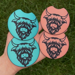 Highland cow character wooden coasters with farm style art on green grass backdrop