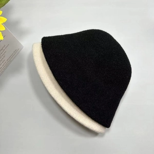 Detailansicht der gestrickten Nerzpelz-Fischerhüte in Schwarz und Creme mit weicher Struktur