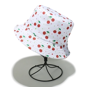 Detailed close-up of white sun hat featuring red cherry prints and colorful polka dots