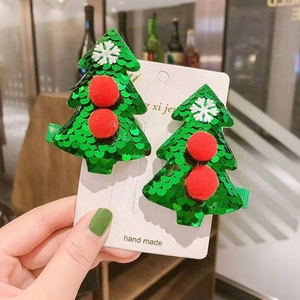 Sparkling green sequin Christmas tree hair clips with red pom poms on a display card