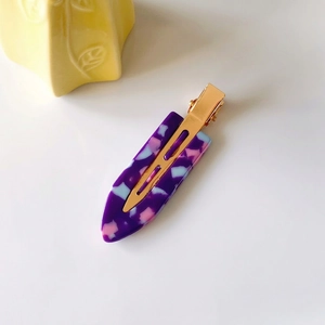 Macro shot of purple acetate hair clip with mosaic texture and golden metal base detail