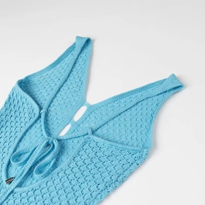 Détail du dos de robe en maille bleue montrant le col en V, les bretelles et le laçage