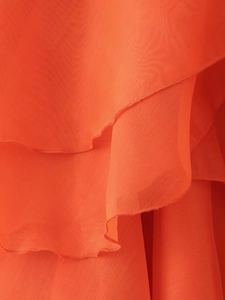Détail d'une robe en mousseline orange avec volants superposés et texture délicate