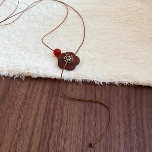 Détail du pendentif fleur en bois rétro avec perle rouge sur cordon tressé