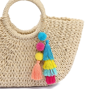 Straw tote bag with colorful bohemian tassel and pom-pom keychain in vibrant colors