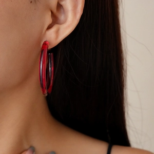 Close-up of marble pattern resin C-shaped hoop earrings worn by a model in red and black