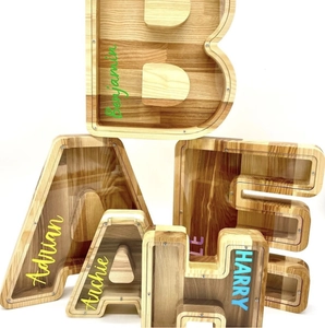Close-up of oak letter piggy banks with clear acrylic panels and custom name prints