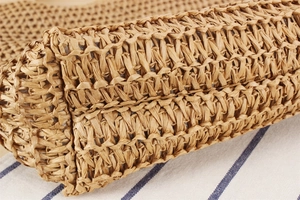 Close-up of the woven texture and bottom corner stitching of the paper rope shoulder bag