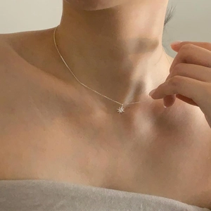 Detailed close-up of a 925 sterling silver starburst pendant necklace on a model