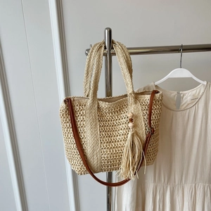 Chic beige woven straw tote bag with brown straps and tassel charm detail