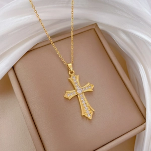 Detail of a gold cross pendant necklace with zircon crystals on white silk background