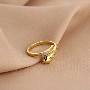 Macro shot of gold snake ring with green stone eyes and zircon pavé on champagne silk