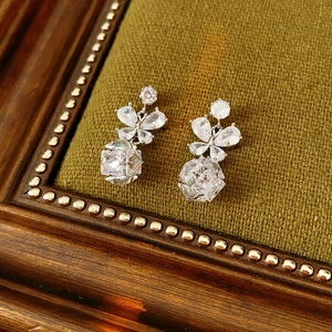 Boucles d'oreilles papillon en argent avec zircone sur fond de tissu vert texturé
