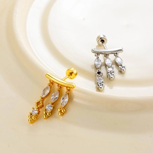 Elegant gold and silver tassel earrings with zircon geometric studs on a ceramic tray