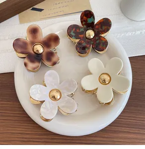 Detailed set of four floral hair claws in tortoiseshell and cream on ceramic plate