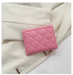 Detail view of a pink quilted faux leather small wallet on beige linen background