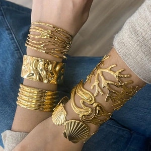 Dettaglio di vari bracciali rigidi in acciaio inossidabile dorato su un modello
