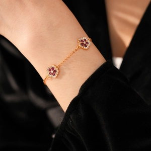 Macro view of 18k gold plated flower bracelet with red stones and zircon pavé on wrist