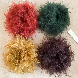 Flat lay of four fluffy faux fur hair ties in red, green, yellow and purple colors