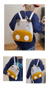 Close-up of yellow and white cartoon cow backpack with embroidered details and straps