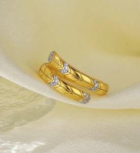 Macro shot of gold-plated snake-shaped earrings with zircon pavé on white satin background