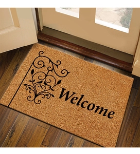 Close-up of coconut fiber welcome mat with black scroll patterns on wooden floor